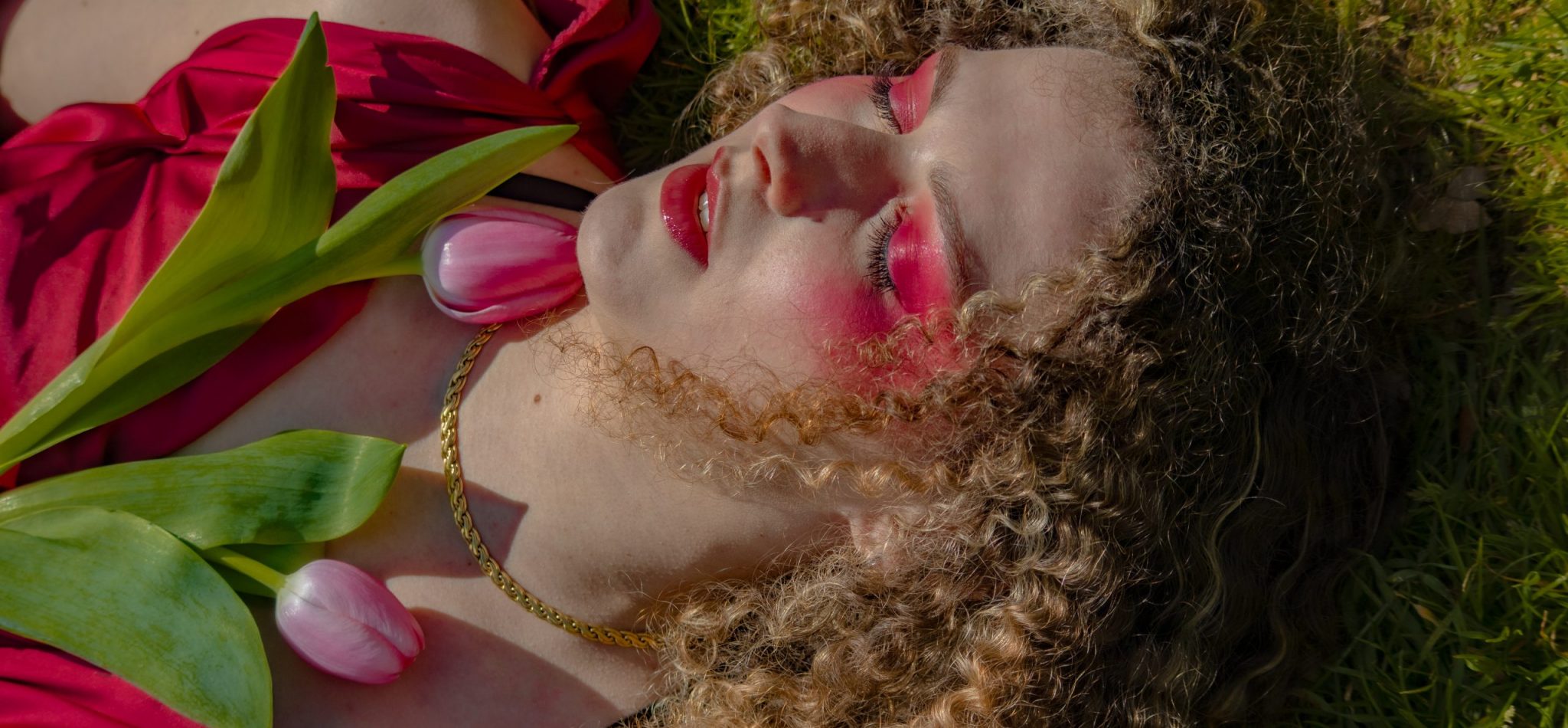 femme allongé dans l'herbe avec maquillage et fleur rose